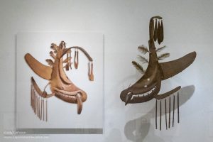 Photograph of a Swan Spirit mask next to a carved wood Arctic Loon mask