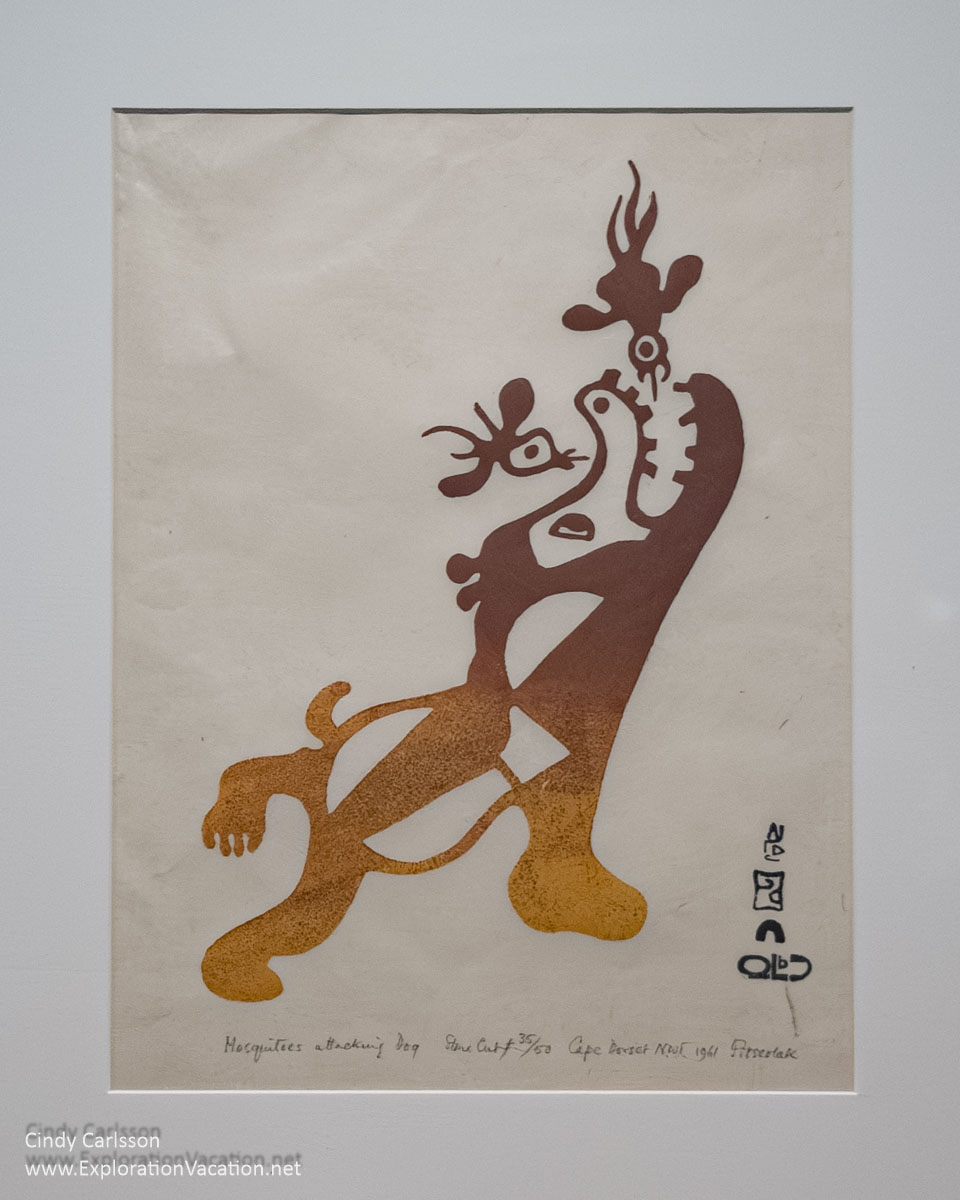 Photo of an Inuit print by Inuit Artist Pitseolak Ashoona titled “Mosquitoes Attacking Dog” at the Dennos Museum Center in Traverse City, Michigan in 2018 © Cindy Carlsson at ExplorationVacation.net