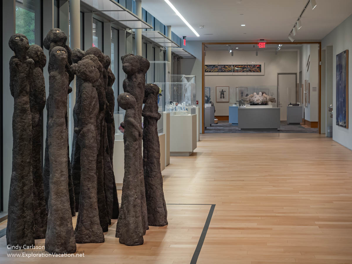 Photo of “Burial Ground” by William Allen, a set of large, dark, mostly abstract, standing figures looking up toward the sky at the Dennos Museum Center in Traverse City, Michigan in 2007 © Cindy Carlsson at ExplorationVacation.net